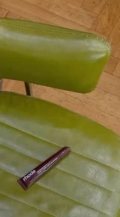 A glossy green leather chair with a burgundy lip tint on the seat.