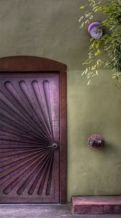 A plum sunburst door set in an olive green wall.