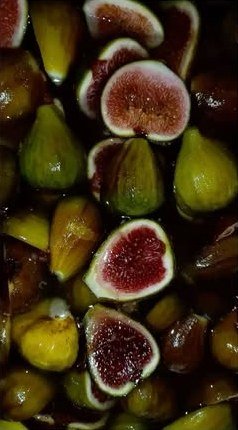 A pile of fresh green and purple figs, some cut open.