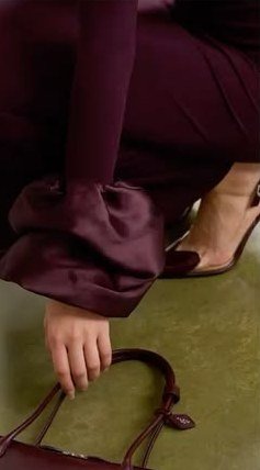Burgundy satin trousers and heels on a green floor.