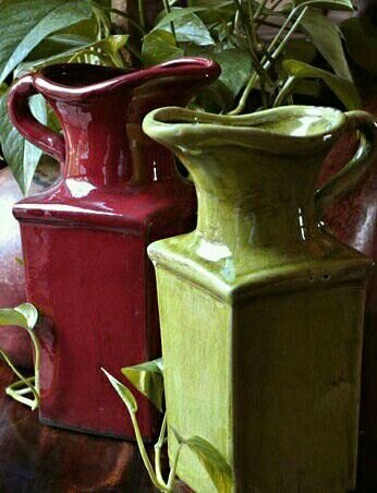 Glazed burgundy and chartreuse ceramic jugs side by side.